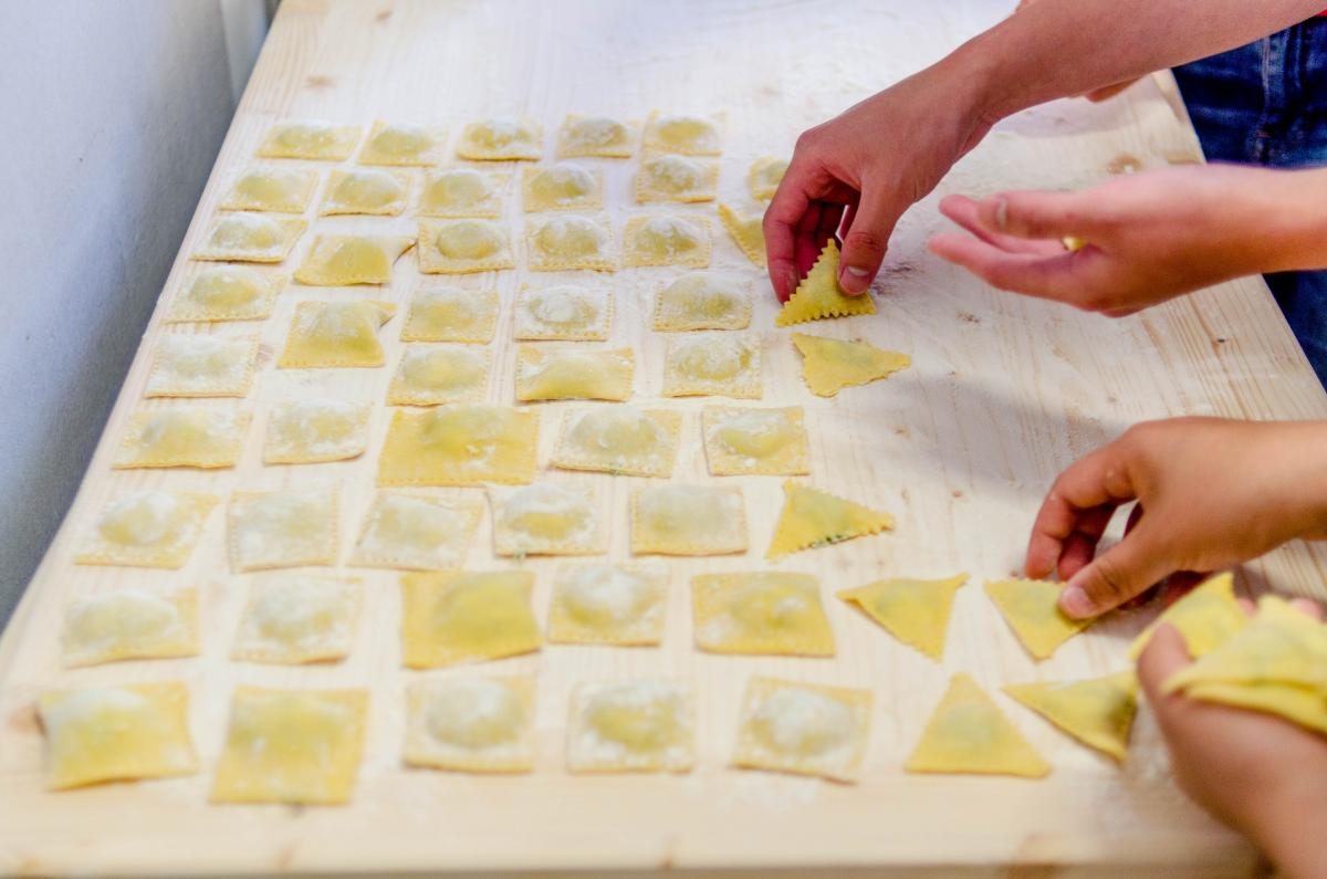 hands shaping square pasta on a wooden table