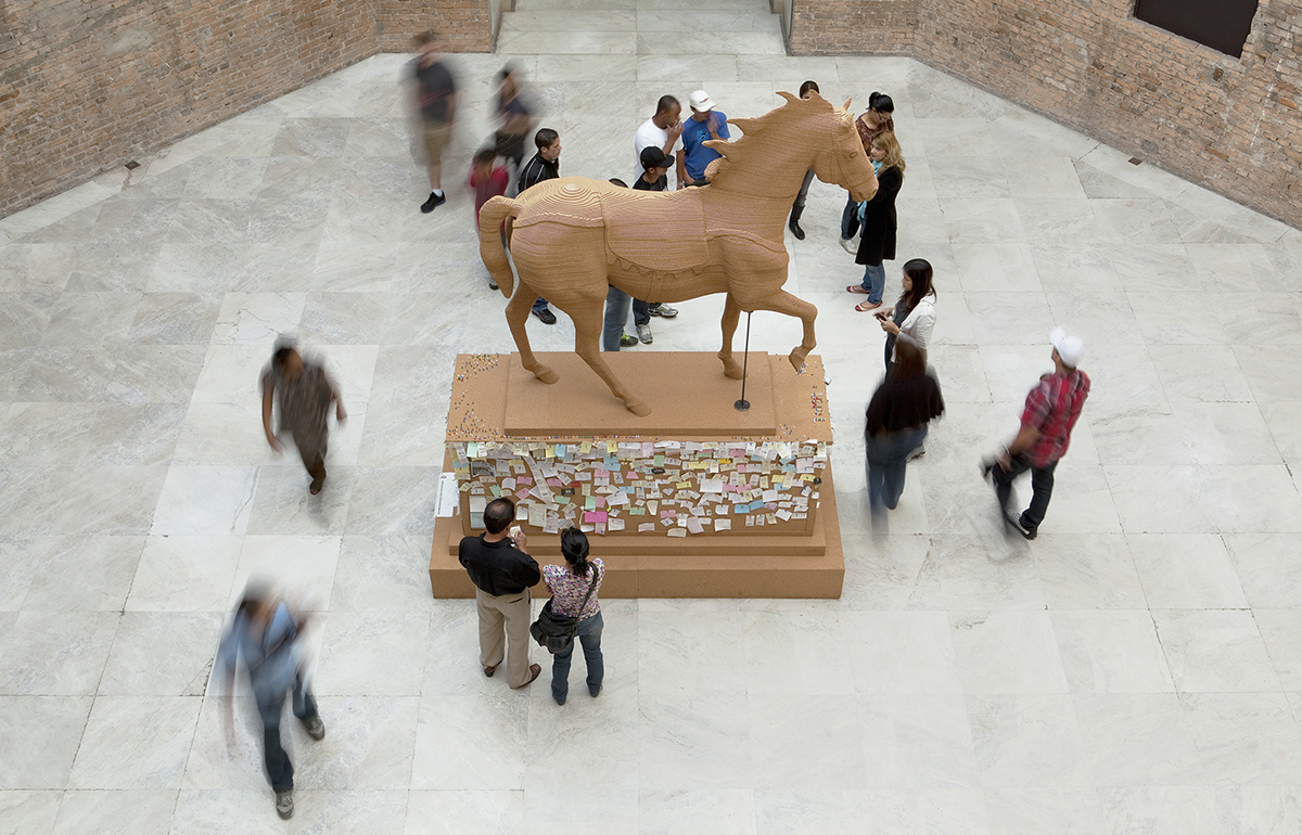 an equestrian statue in a gallery space with people around