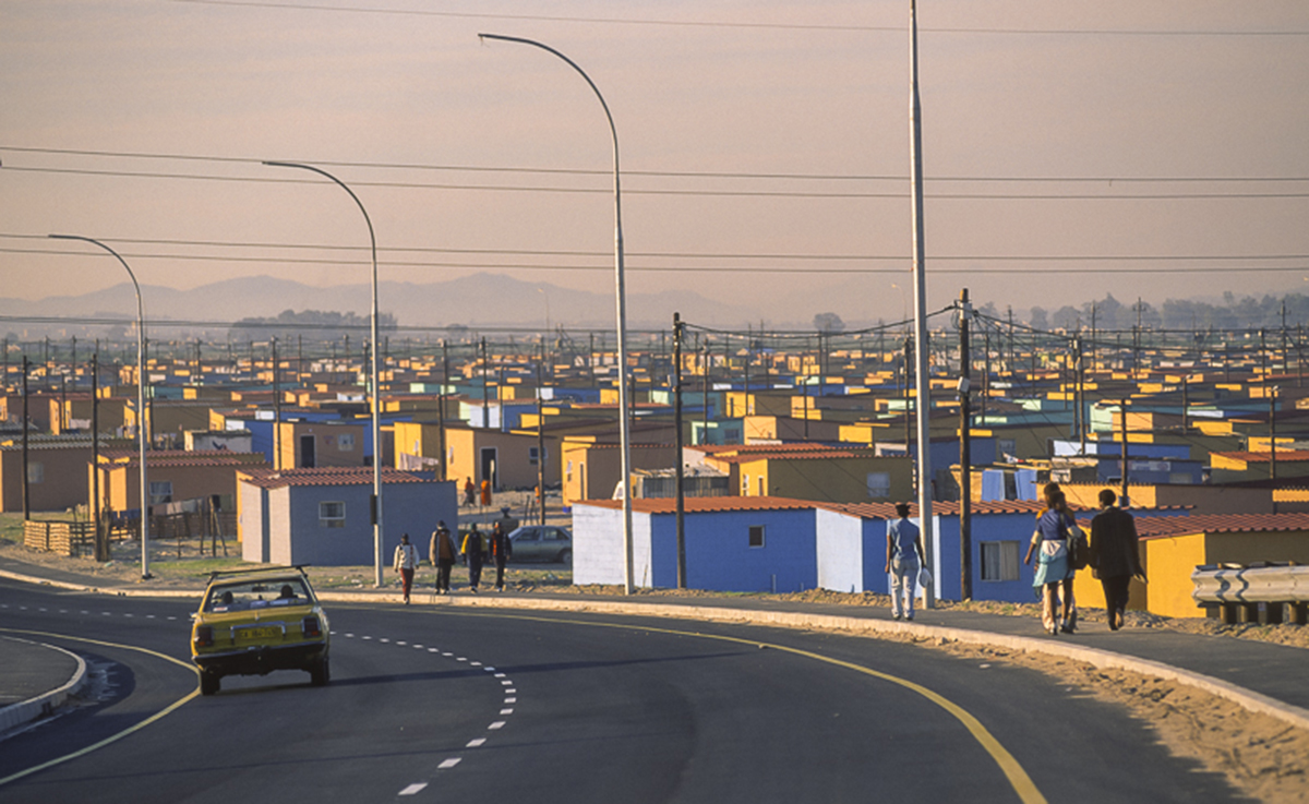 a view of small modests houses from the road in front of a sunset