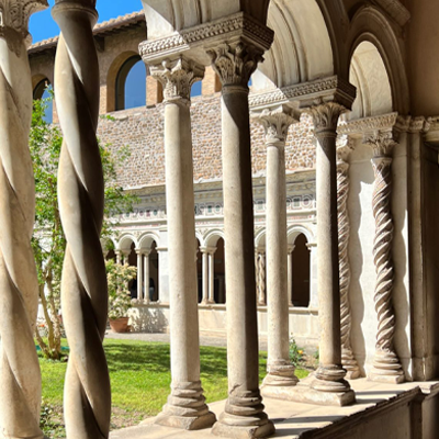 columns of a building with casted shadows outside near a courtyard