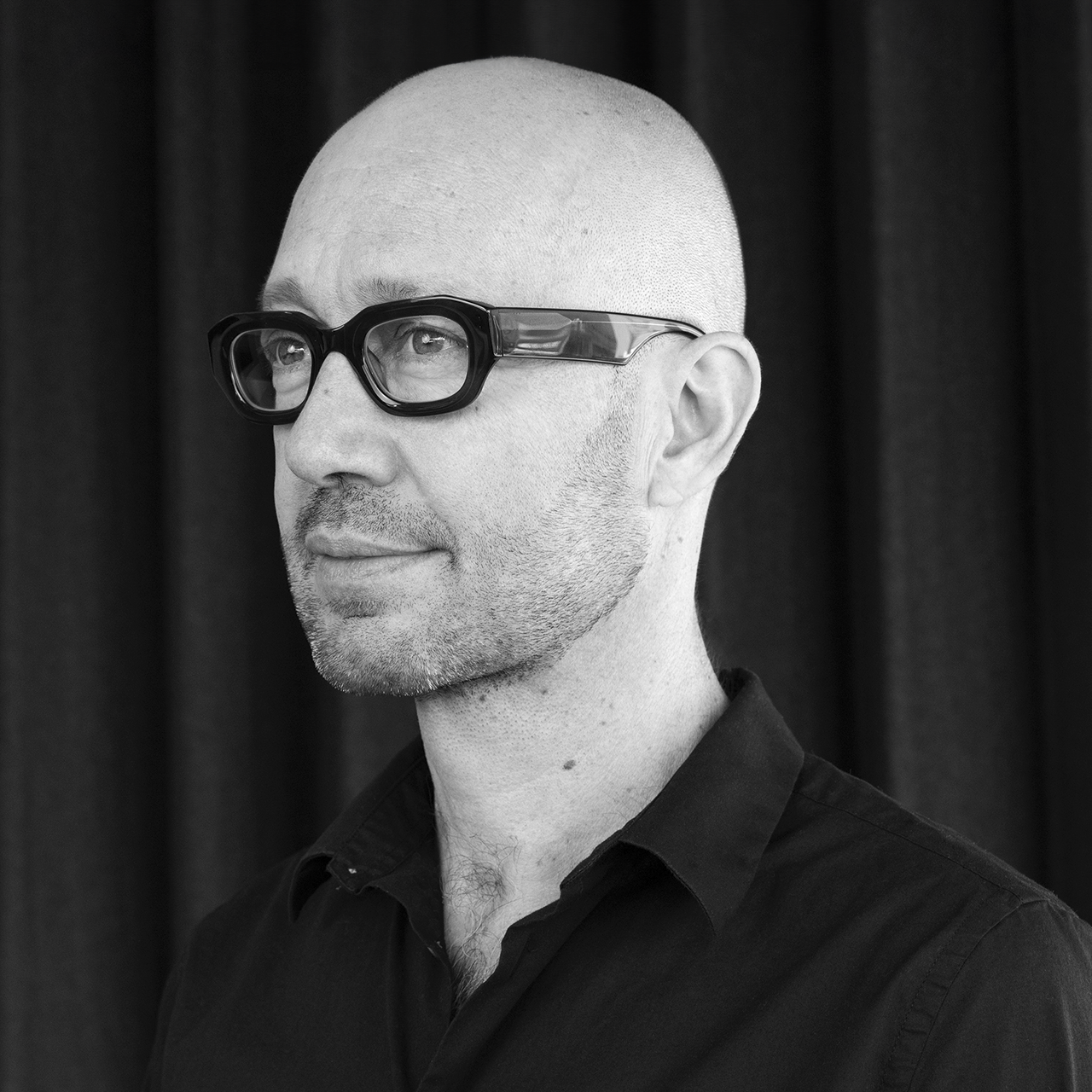 Man wearing dark shirt and black framed glasses