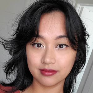 Selfie of a Filipino-American person wearing makeup, with long black hair and a red shirt.