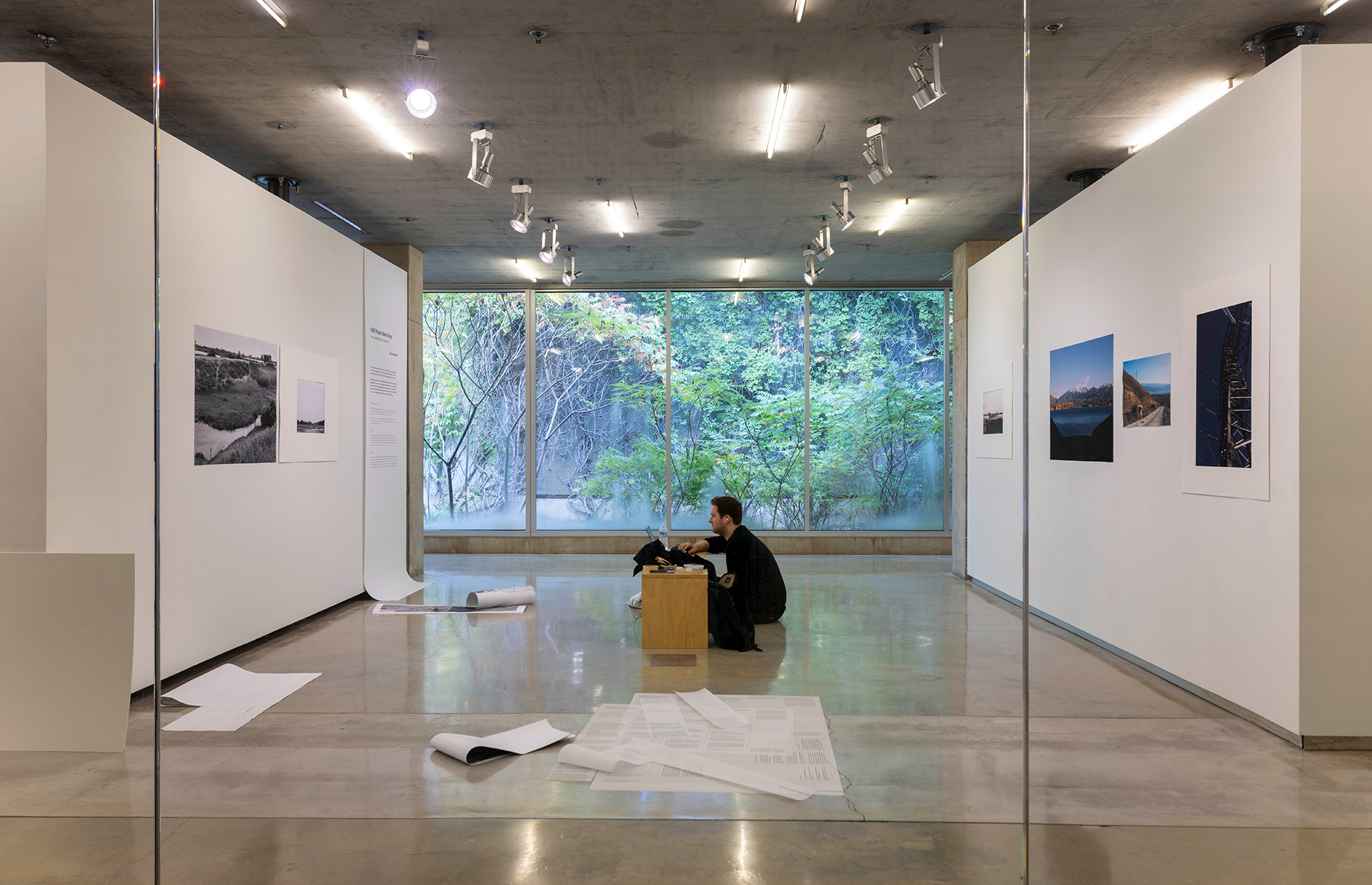 Man instaling an exhibit in a gallery as viewed through a glass wall