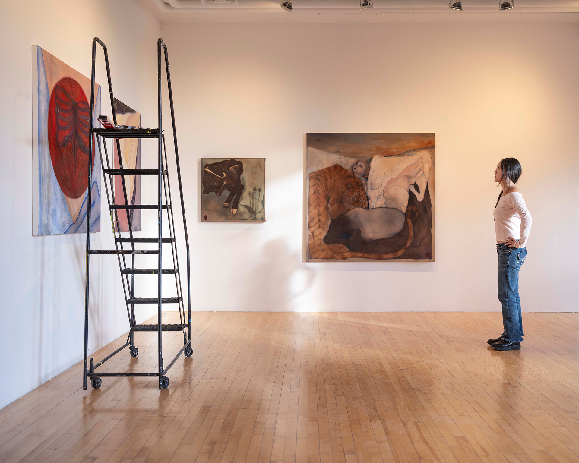 woman looking at canvas hung on gallery wall