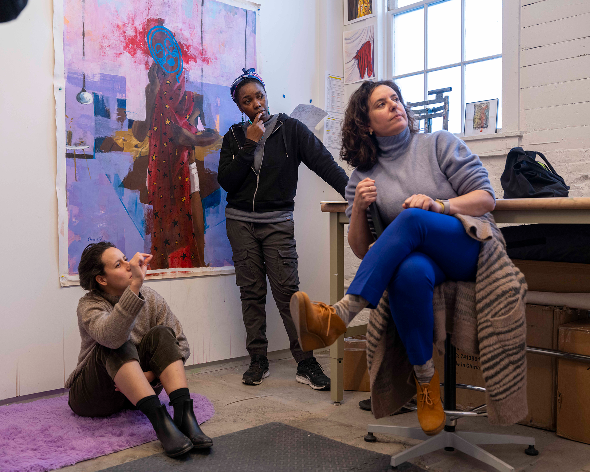 Students and professor gathered in a studio to review artwork.