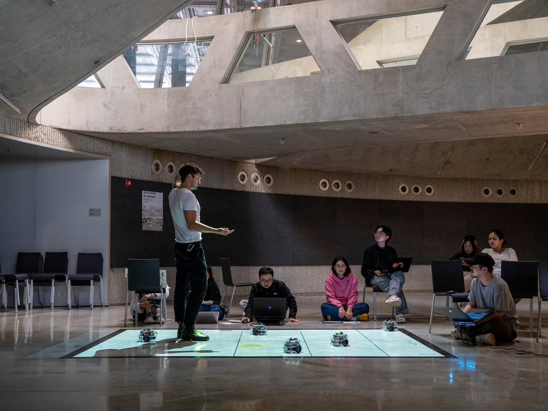 Students seated on the floor demonstrating small robots