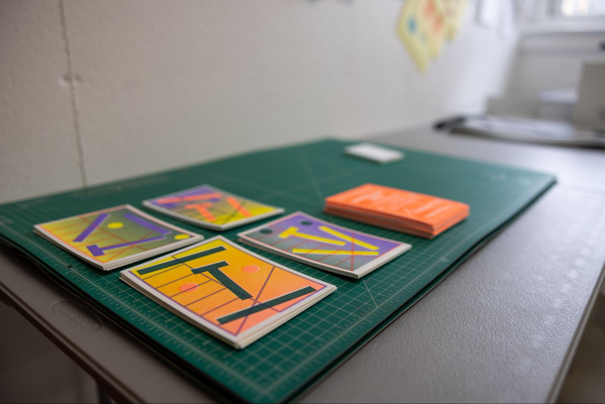 Brightly colored posters stacked on top of a green cutting mat.