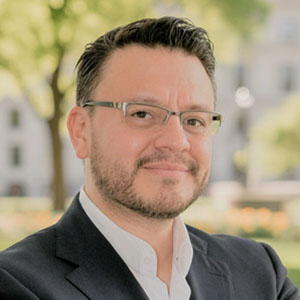 Man with glasses wearing a suit jacket and white button down shirt 