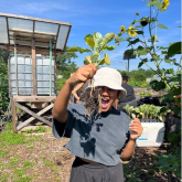 woman holding up a plant smiling on a farm