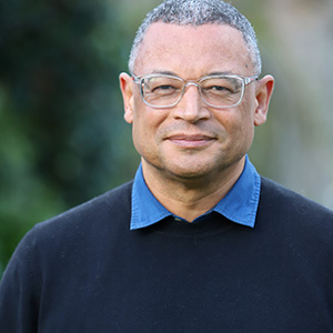 A person with glasses wearing a blue sweater