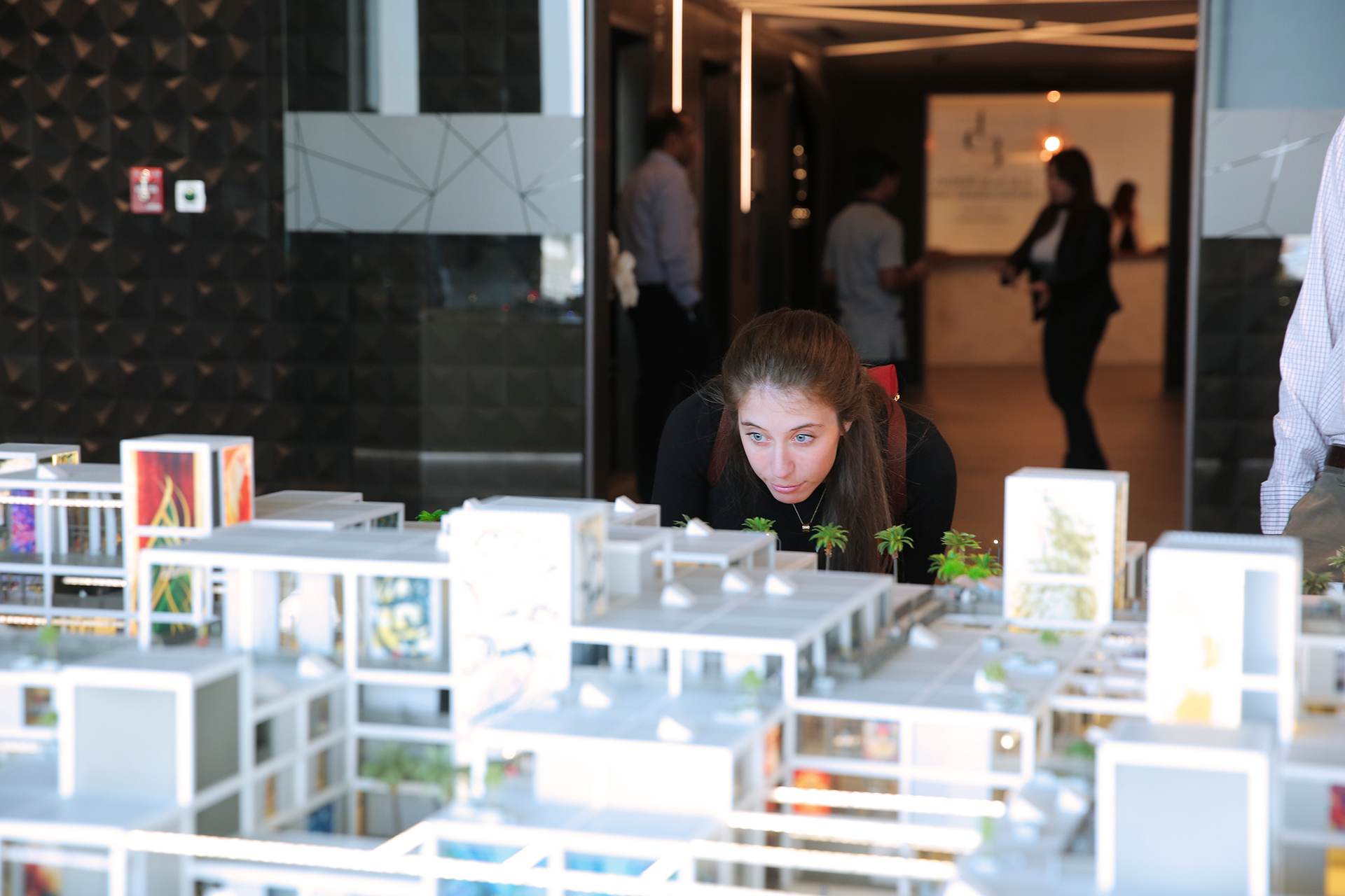 Woman examines architectural model of an urban streetscape.