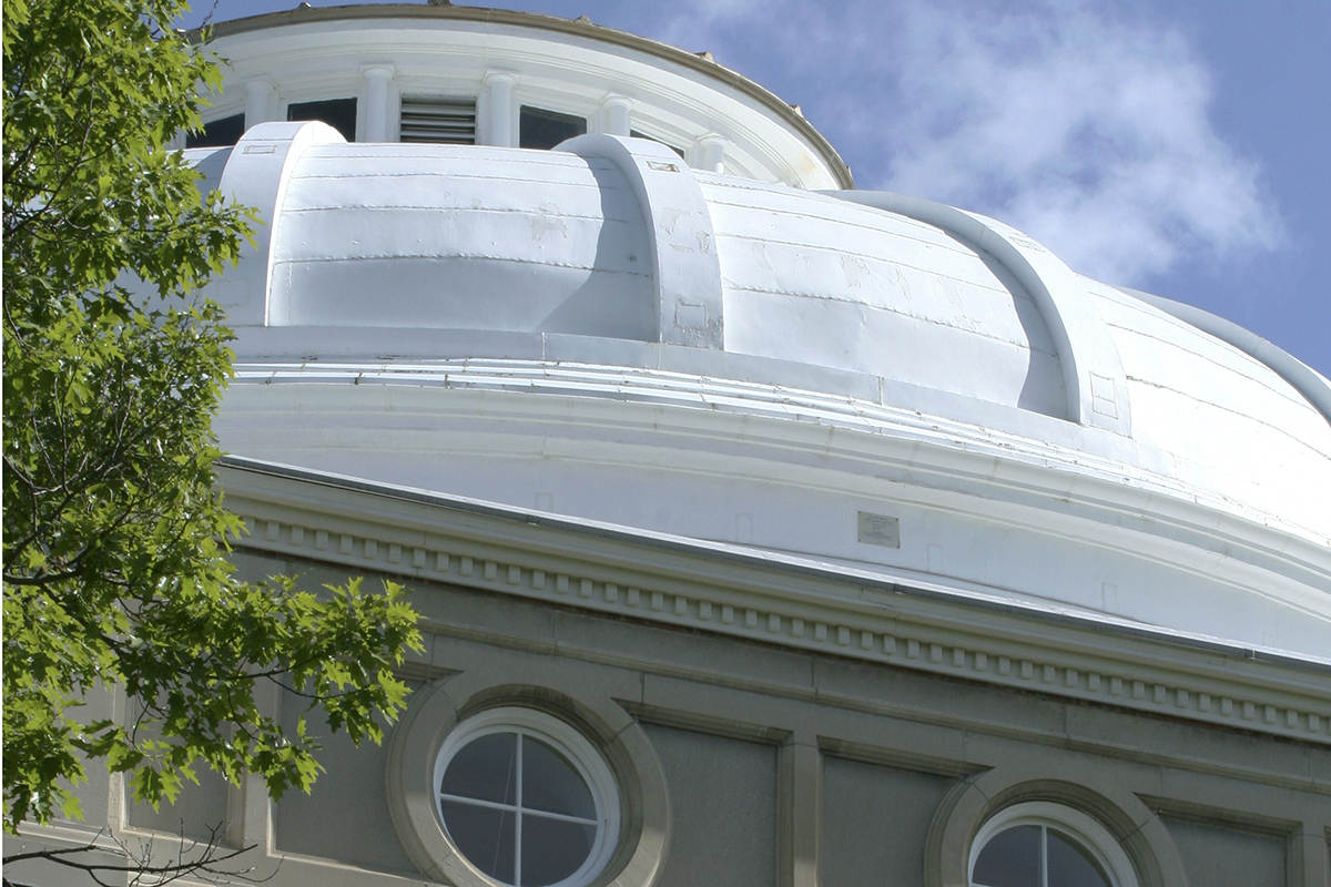 White building dome against a blue sky with cloud cover
