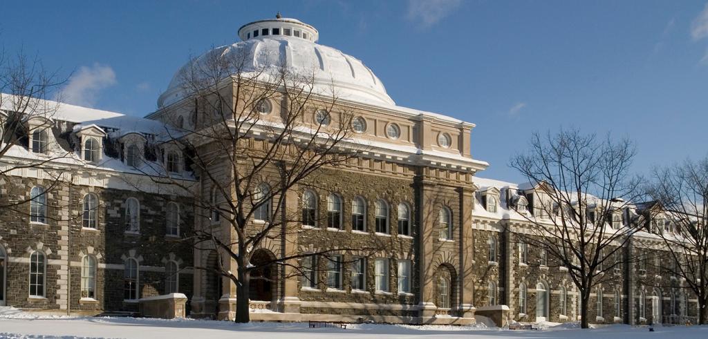 big histiorical college building with a dome, outside on a sunny day with snow on the ground