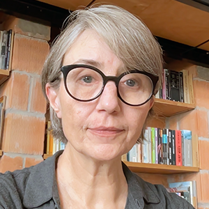 Woman with short grey hair wearing round black glasses