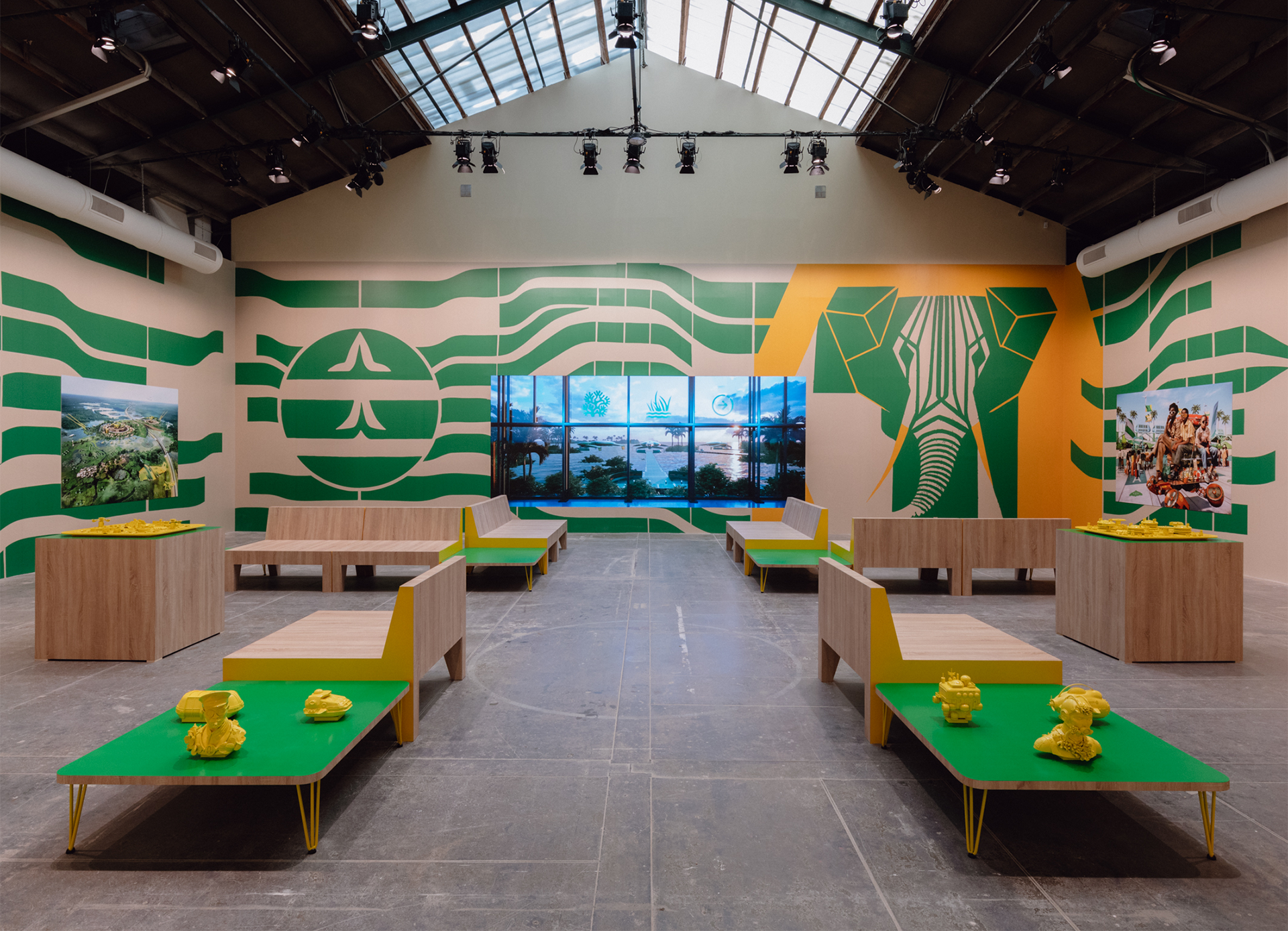 Fictional waiting lounge featuring bright green tables, yellow sculptures, and hung travel posters