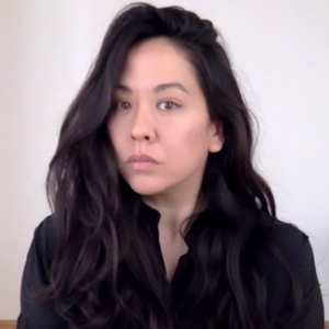 A woman with long dark hair looking serious