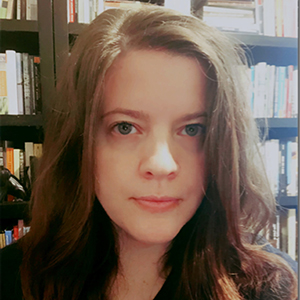 a woman with long brown hair in front of a bookshelf