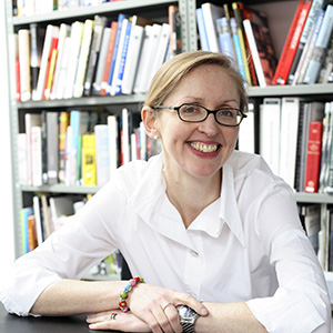 Portrait picture of a woman with glasses in front of a bookshelf