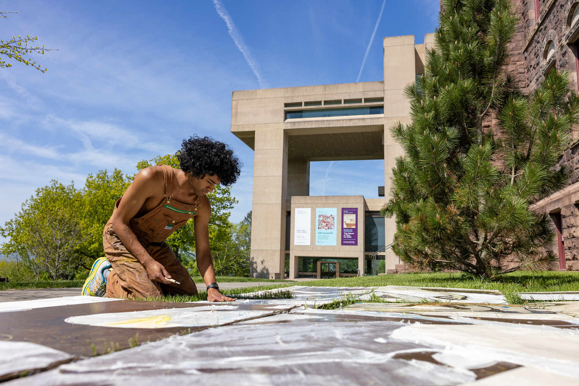 https://aap.cornell.edu/Student%20wearing%20overalls%20kneeling%20in%20the%20grass%20working%20on%20an%20art%20project