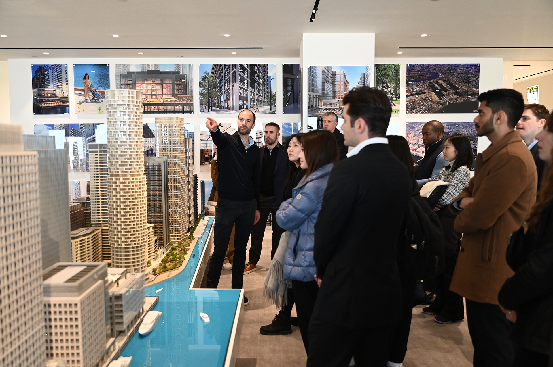 Man in front of a model of a city speaking to a group of students