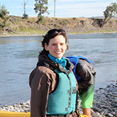 portrait of a woman standing on a shoreline wearing a blue life jacket
