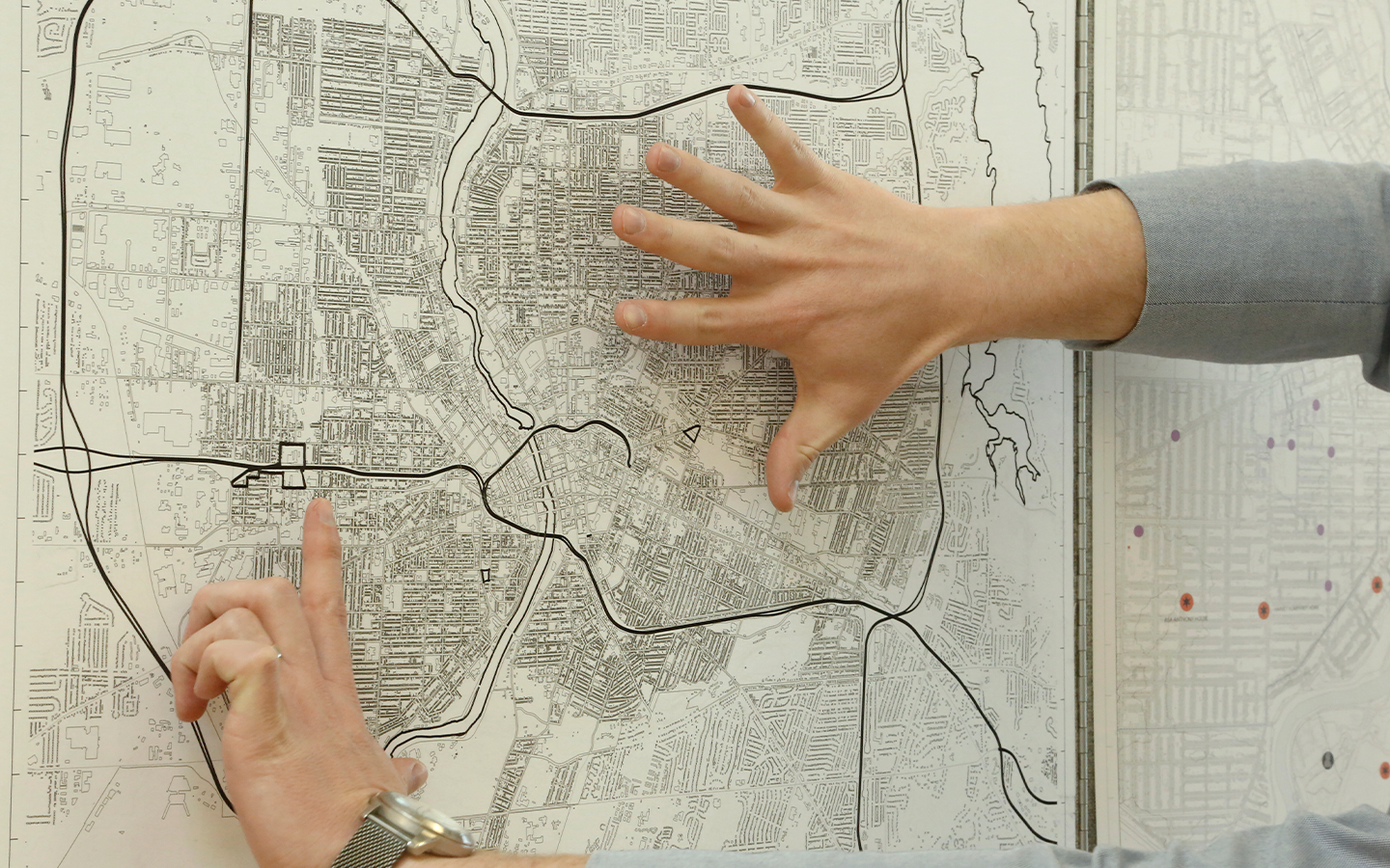 A person with hands on top of a map on the wall.