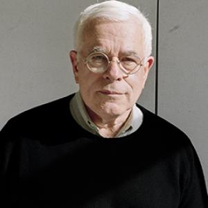 a white man with short white hair and glasses wearing a black sweater