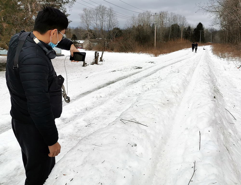 student taking cellphone picture of snowy path
