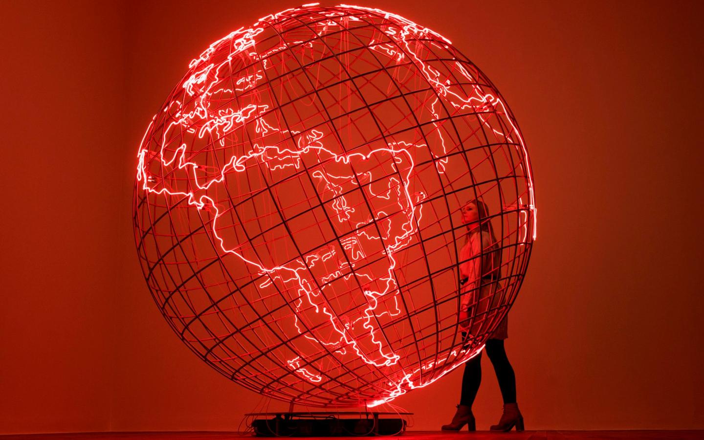 A person stands next to a large, translucent globe that glows red.