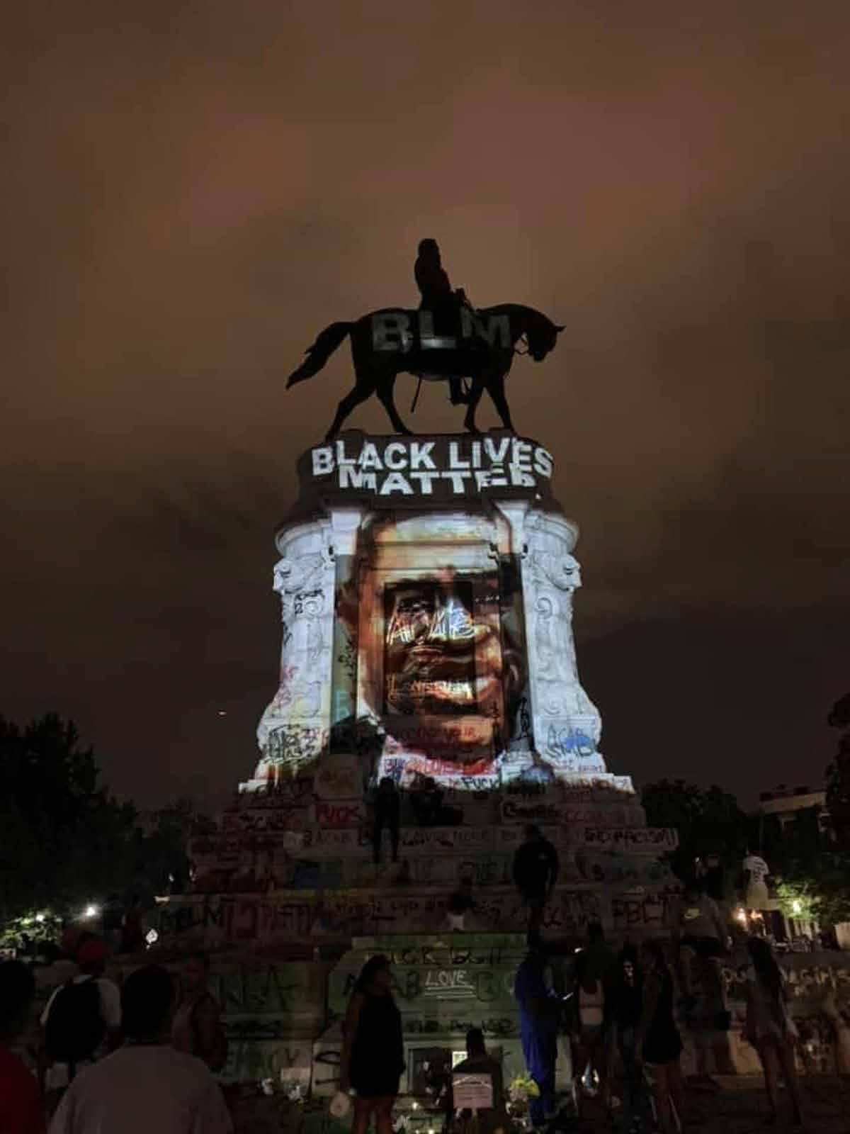 A large statue with a projected image of a person's face and text.