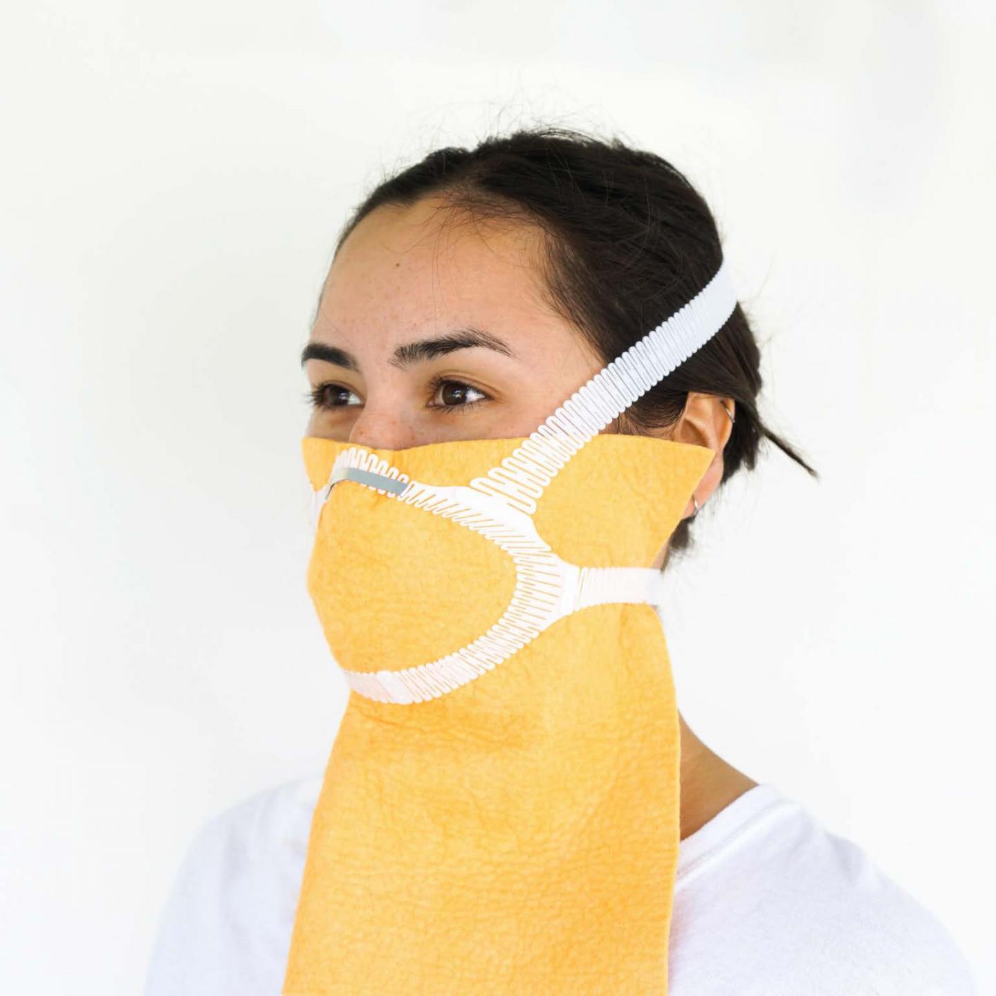 Person wearing a yellow face mask with white straps.