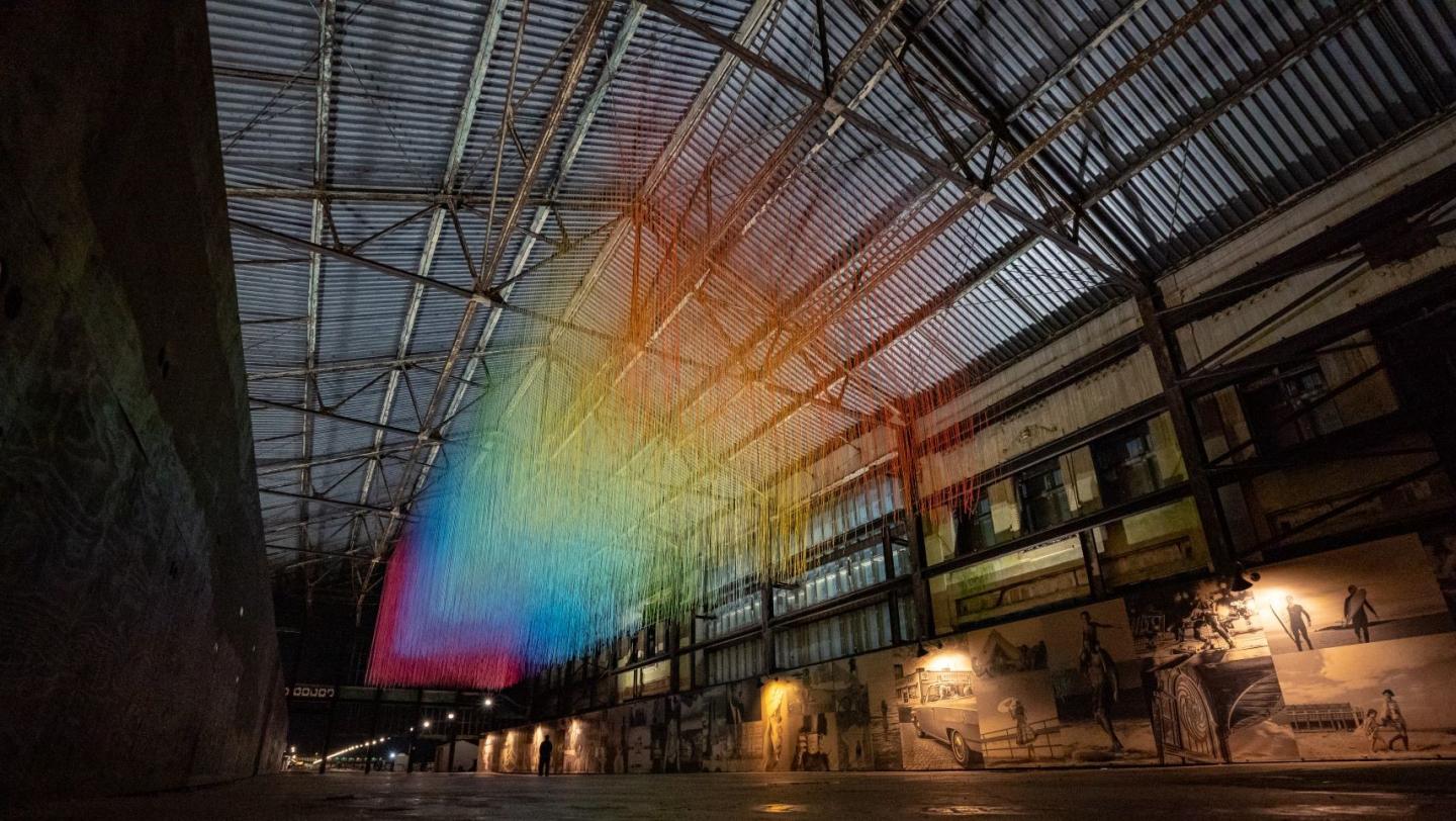rainbow-clored patters projected in an atrium space under metal beams and a metal ceiling