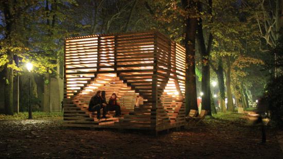 People sitting in a wooden sculpture/structure in outdoor setting at night