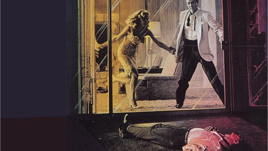 A woman grabbing the hand of a man standing in front of a sliding glass door with another man laying on the ground on the other side who appears to be dead.