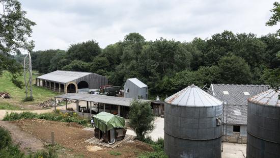Steel tanks and sheet metal buildings surrounded by trees and grass.