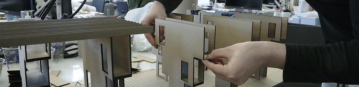 Hands adjusting an architectural model made of cardboard