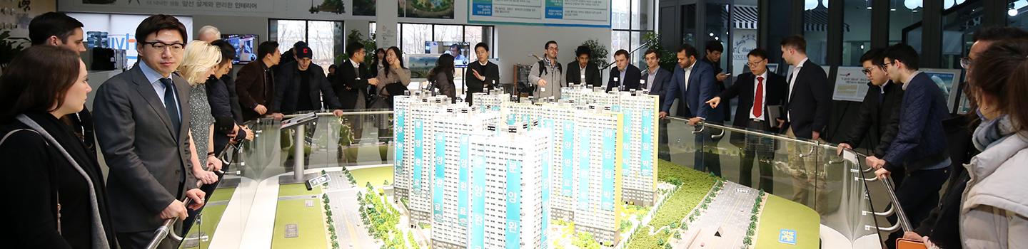 People stand around a large scale model of city buildings