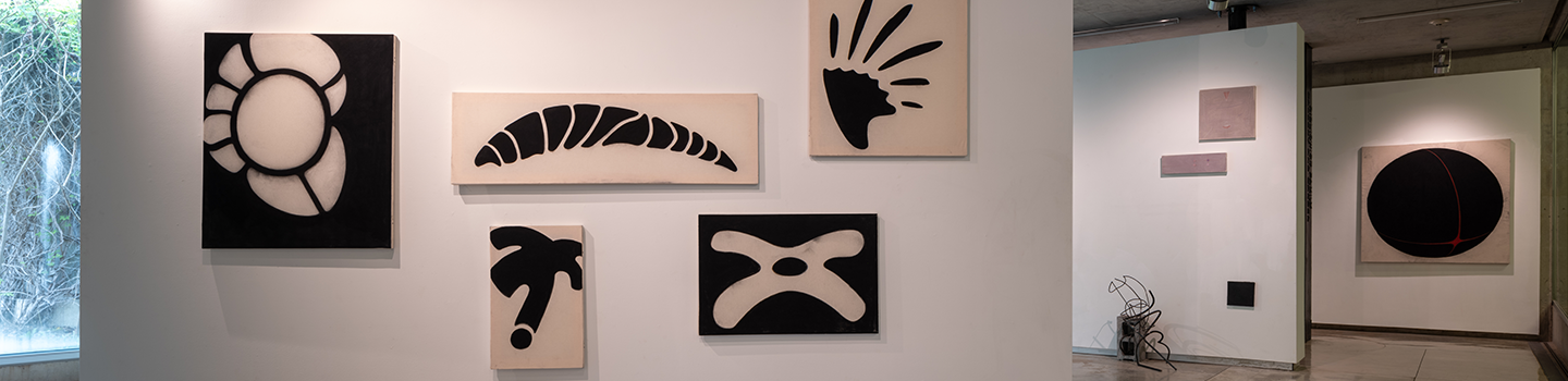 View of three gallery walls with charcoal and painted canvases and a sculpture made of metal.