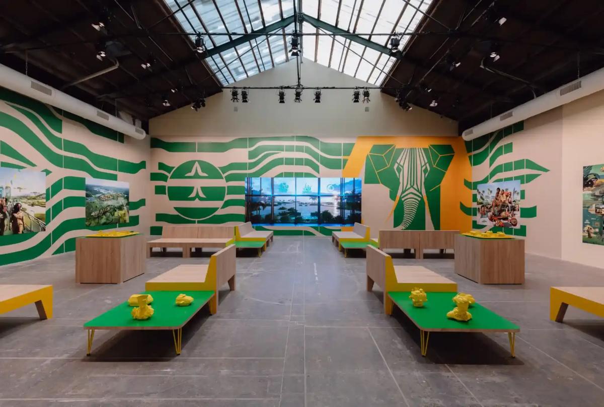 A large room with green and yellow objects containing photos and a stylized elephant on the wall.