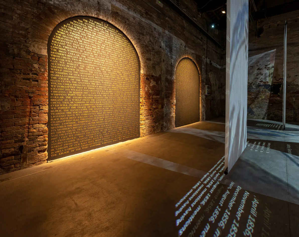 Installation with text on a brick wall and projections on white hanging cloth