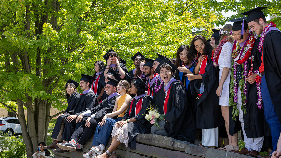 students wearing graduation caps and gowns gathering for a photo