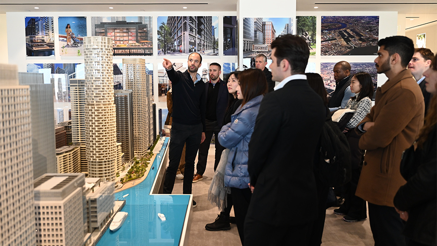 A man presents model buildings while a group watches.