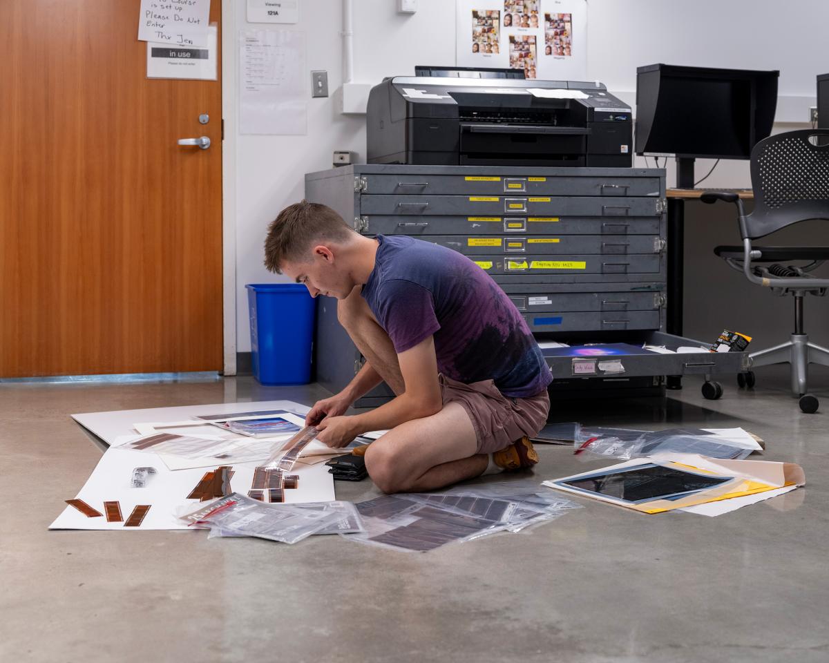 a person kneeling down looking at film strips on the floor