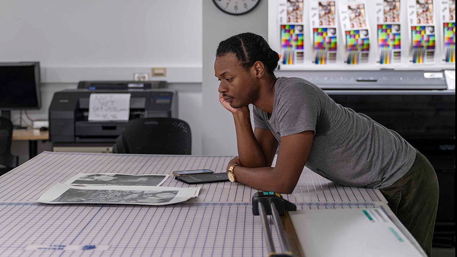 Person leaning over a grid patterned table examining photographs.