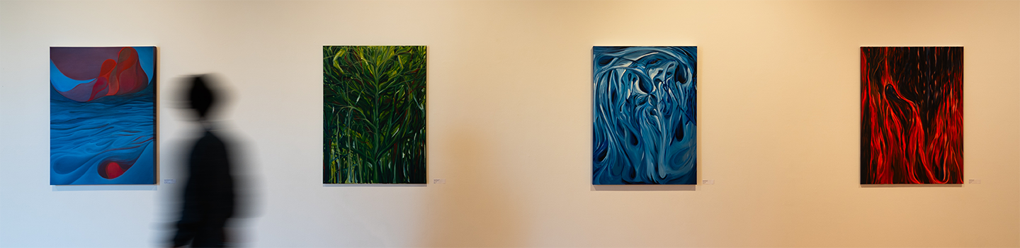 A series of painted canvases displayed on a wall with a person walking by.