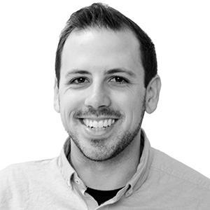 Light-skinned man with short dark hair wearing a light shirt against light background