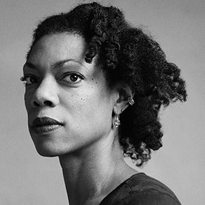 A black and white photo of a woman with dark curly hair.