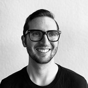 A black and white photo of a man with glasses smiling