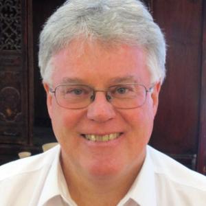 a person with white gray hair and a white collared shirt.