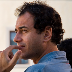 Profile portrait of a person with brown hair, wearing a light blue shirt, gazing into the distance.